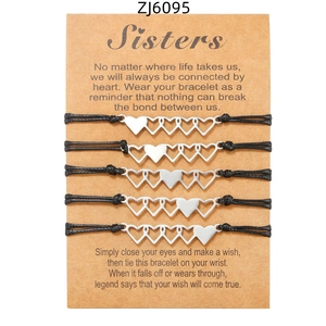 Set di cinque braccialetti dell'amicizia intrecciati con ciondoli a cuore su carta