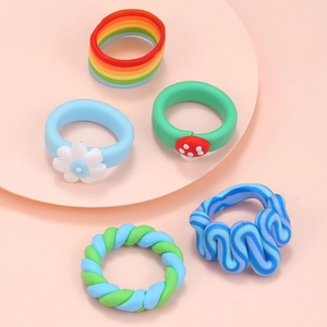 Set of five colorful clay rings with daisy and mushroom motifs on a pastel display stand