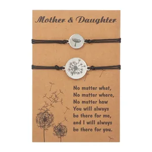 Detail of mother and daughter woven bracelets with engraved dandelion charms on card