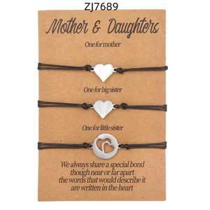 Dettaglio di tre braccialetti dell'amicizia intrecciati con cuore su cartoncino
