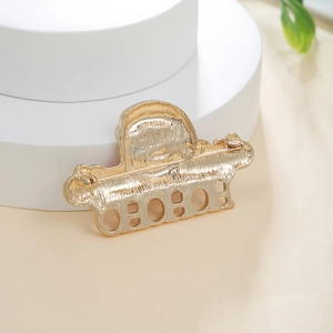 Macro shot of the gold alloy brooch back featuring brushed metal texture and safety pin