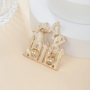 Detail view of the golden castle brooch back showing pin clasp and brushed metal texture