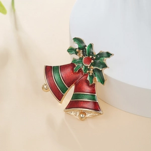 Detailed close-up of a festive Christmas bell brooch with red and green enamel and holly leaves