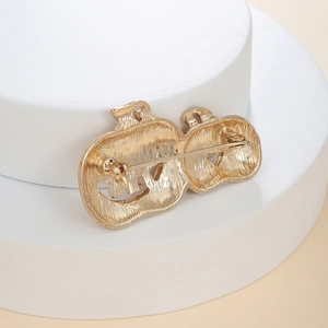 Macro detail of pumpkin brooch back showing gold metal texture and safety pin clasp