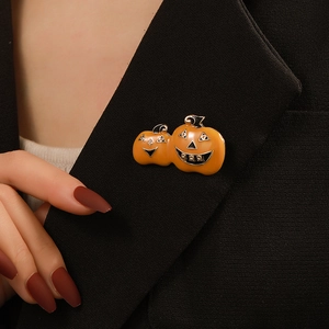 Detail of a festive Halloween double pumpkin brooch with orange enamel on a black blazer