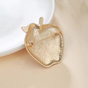 Detailed back view of a gold strawberry brooch showing pin fastener and radial texture