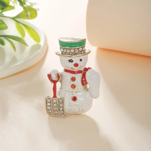 Detail of enameled snowman brooch with green hat, red scarf and shimmering rhinestones
