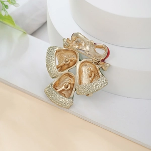 Detail of Christmas bell brooch featuring red enamel bow and gold-tone pin clasp backing