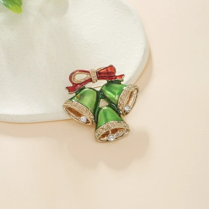 Macro detail of Christmas bell brooch with green enamel, red bow, and crystal accents