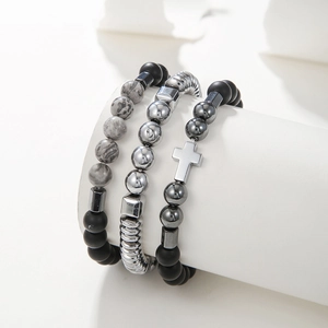 Detail of beaded bracelet set with cross charm and map stone on a display stand