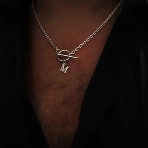 Détail du collier argenté avec fermoir à bascule OT et pendentif lettre M audacieuse