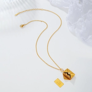 Macro view of gold envelope necklace with Love You engraving on polished stainless steel