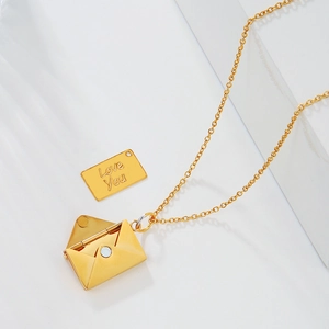 Macro detail of golden envelope pendant opening to show a card engraved with Love You