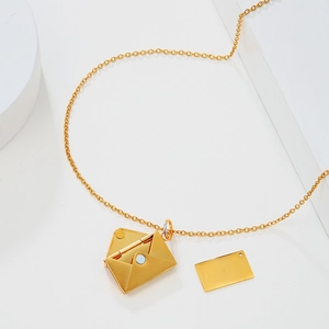 Detailed view of an open golden envelope locket necklace with a removable metal insert