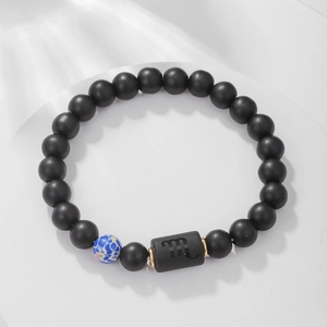 Detalle del amuleto de Escorpio en la pulsera elástica de cuentas de ágata negra mate