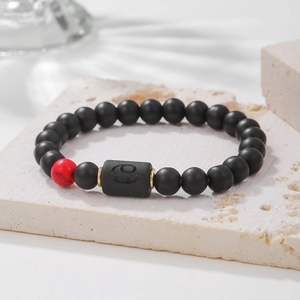 Detalle macro de cuentas de ónice negro mate y dije del signo Cáncer en pulsera elástica