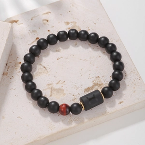 Primer plano del dije de Tauro en pulsera de cuentas de ágata negra con ojo de tigre rojo