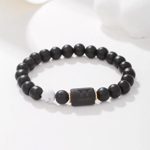 Detalle macro de pulsera Géminis con cuentas de ágata negra mate y anillos dorados