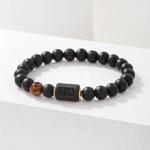 Detalle de la cuenta del signo Virgo y piedras de ágata negra con espaciadores dorados