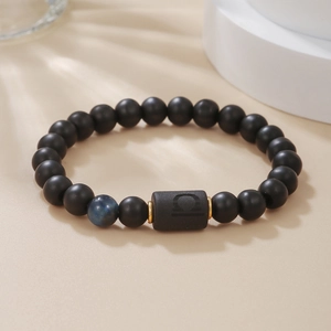 Detalle de pulsera del zodiaco Libra con cuentas negras mate, piedra azul y piezas de oro