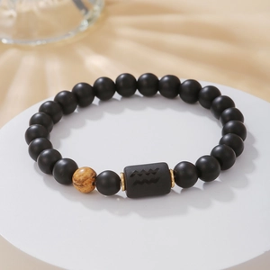 Detalle macro de la cuenta del signo Acuario en pulsera de cuentas de ágata negra mate