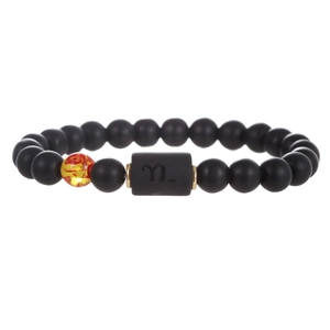 Pulsera de Capricornio con cuentas negras mates y piedra de ámbar en fondo blanco
