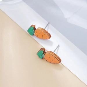 Detailed close-up of cute wooden carrot stud earrings with green leaves and orange body