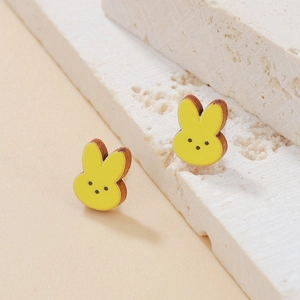 Detalle de pendientes de madera con forma de conejo amarillo y textura de madera natural