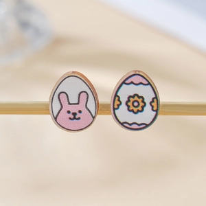 Detalle macro de pendientes de madera en forma de huevo con conejo rosa y flores de colores
