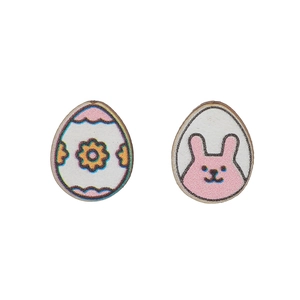 Detalle de pendientes de madera con huevo de Pascua y conejo rosa sobre fondo blanco