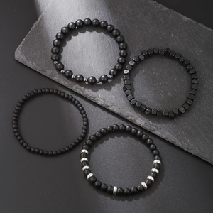 Men's 4-piece bracelet set with matte black beads and hematite stones on grey slate