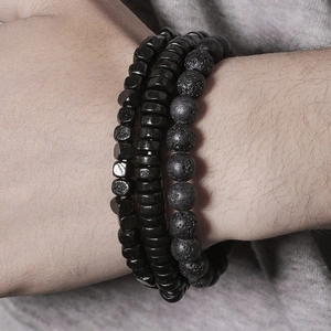 Close-up of triple-layered black matte lava stone and hematite beaded bracelets on wrist
