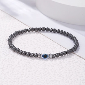 Detail van herenarmband met donkere hematiet kralen en centraal blauw boze oog ornament