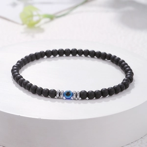 Detailopname van een 4mm zwarte matte kralenarmband met blauwe Evil Eye en zilveren tussenstukjes