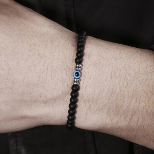 Detailopname van matzwarte kralenarmband met blauw evil eye bedeltje om de pols