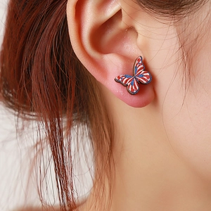 Macro view of butterfly wooden stud earring with US flag pattern worn on ear lobe