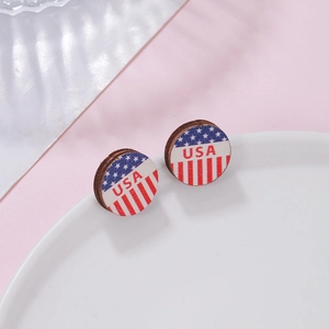 Close-up of circular wooden earrings with USA flag pattern and letters on white plate