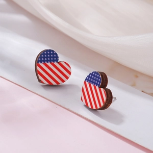 Macro detail of heart-shaped wooden earrings with American flag pattern on white silk
