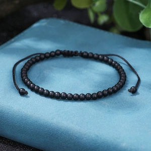 Detailed close-up of matte black beads on adjustable woven cord with flat knot
