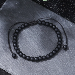 Detailed macro view of 8mm matte black agate beaded bracelet with adjustable woven knot