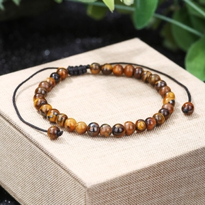 Macro shot of 8mm tiger eye stone beads with adjustable black braided cord on a jewelry box
