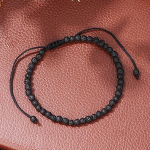 Detail of adjustable black lava stone beaded bracelet with woven cord on leather