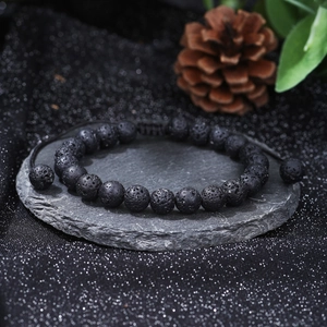 Macro detail of natural black lava stone beads on adjustable woven men's bracelet