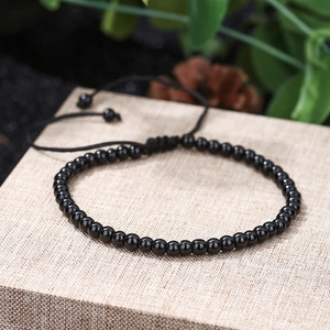 Close-up of polished black beaded bracelet with adjustable cord on decorative platform
