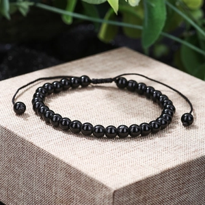 Detail of a 6-8mm polished black bead bracelet with adjustable woven knot and natural beads