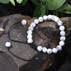 Close-up of white turquoise beaded bracelet with adjustable black braided cord on a rock
