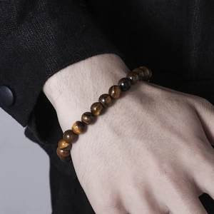 Close-up of a 8mm natural tiger eye beaded bracelet worn by a man in a black suit
