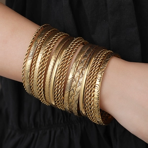 Detailed view of 19-piece vintage gold-tone hammered metal bangles worn in a stack