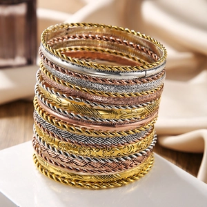 Detailed close-up of mixed metal bangles showing twisted and floral engraved textures