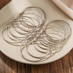 Detailed view of silver stackable bangle set with smooth and twisted rope texture